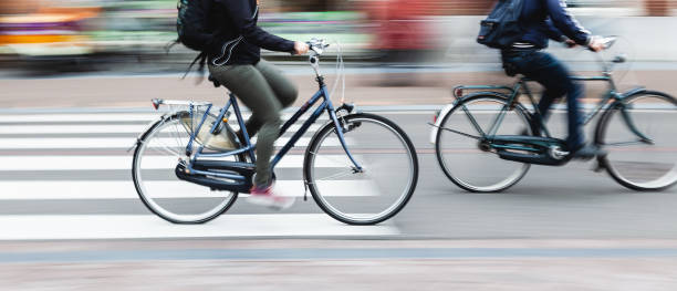 bicycle riders on a city street - crossing people panoramic road imagens e fotografias de stock