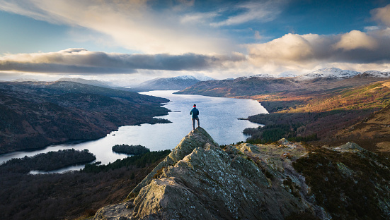 Hiker on the summit of Ben A'an, Scottish Highlands at sunset
