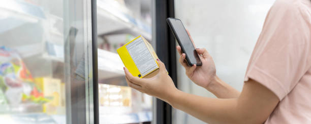 primer plano de joven empresaria asiática con mascarilla está comprando carne y escaneando código de barras con teléfono inteligente en el supermercado. - ice pack fotos fotografías e imágenes de stock