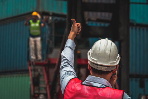istock Industrial worker works with co-worker at overseas shipping container yard . Logistics supply chain management and international goods export concept . 1464893714