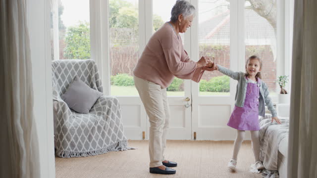 cute little girl dancing with grandmother funny granny having fun dance with granddaughter celebrating family weekend at home 4k