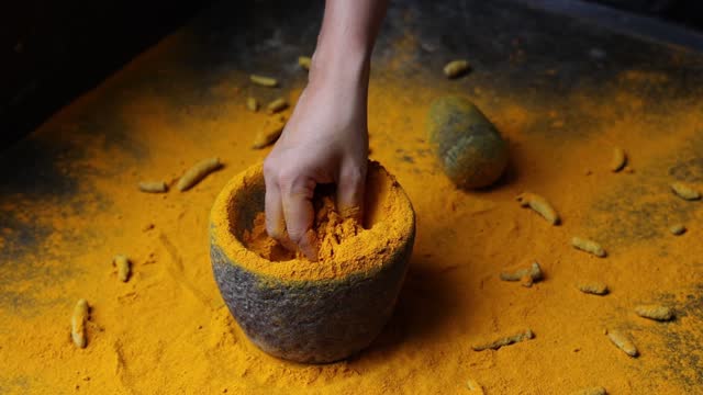 Woman hand powdering Indian spices turmeric powder stone mortar Kerala India
