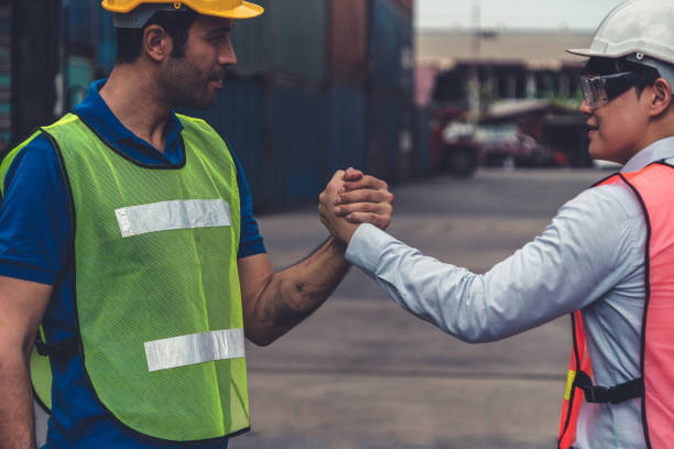istock Industrial worker works with co-worker at overseas shipping container yard . Logistics supply chain management and international goods export concept . 1464896764