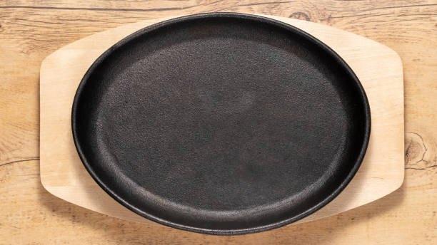 istock Empty cast iron black plate on a light wooden background 1464917871