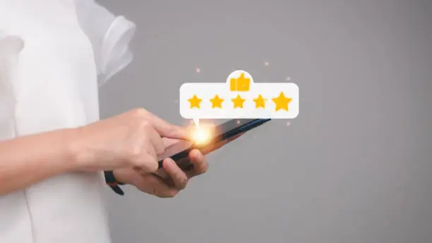 Photo of Hand pressing on smartphone screen with gold five star rating feedback icon and press level excellent rank for giving best score point to review the service , business concept