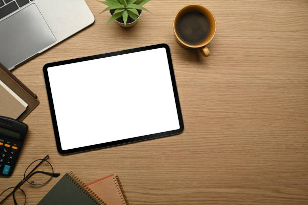 istock Digital tablet with empty screen, eyeglasses, notebook and coffee cup on wooden table. 1464932954