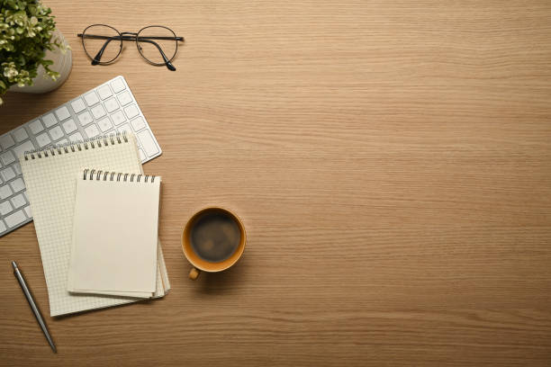 istock Simple workplace with notebooks, eyeglasses, keyboard and coffee cup on wooden desk. 1464932955