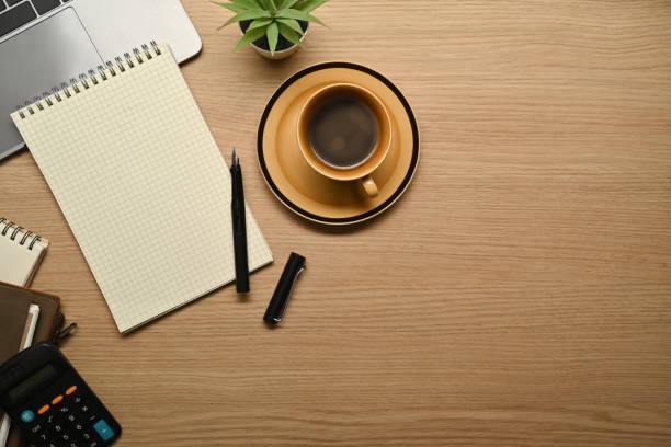 istock Top view of coffee cup, blank notepad, calculator and laptop computer on wooden table. 1464932958