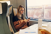 Teenage girl travelling on modern train and reading a book