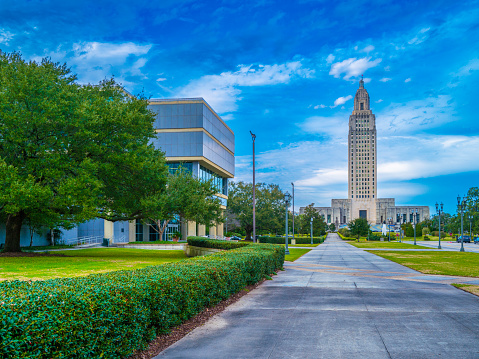 Louisiana State Capitol and the sidewalks with modern buildings, street lamps, and manicured green garden in Downtown Baton Rouge, the second largest city in the state on the banks of the Mississippi River, USA