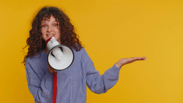 istock Woman talking with megaphone, proclaiming news, loudly announcing advertisement pointing empty place 1464943729
