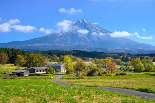 A scenic shot of the famous Mount Fuji behind a rural locality on a sunny summer day