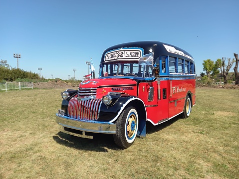 San Isidro, Argentina – October 08, 2022: old red Chevrolet 1946 bus for public passenger transport in Buenos Aires. Traditional fileteado ornaments. Autoclasica 2022 classic car show.