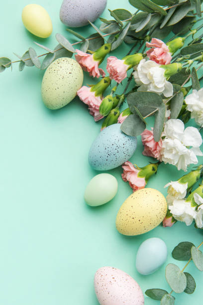 istock Easter colored eggs and a bouquet of white and pink carnations with eucalyptus branches on a soft green background. 1464953981