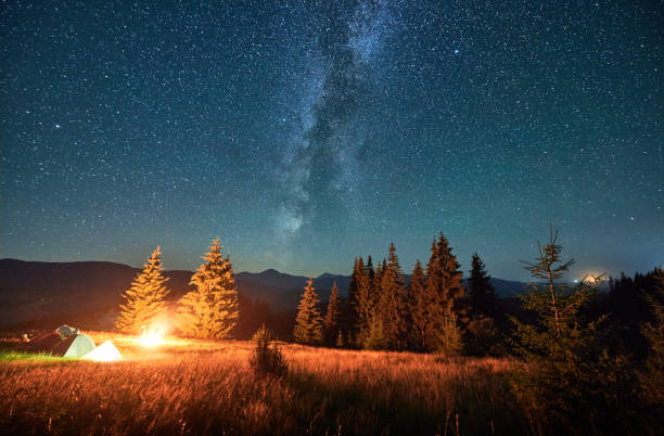 istock Night camping in mountains under starry sky with Milky way. 1464956532