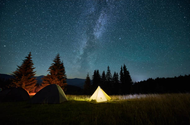 istock Night camping in mountains under starry sky with Milky way. 1464956647