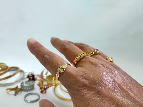 Gold and platinum jewelry. White gem ring on finger of human hand isolated on light background.