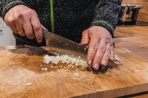 istock Man in a kitchen chopping onions with a big knife. 1464959027