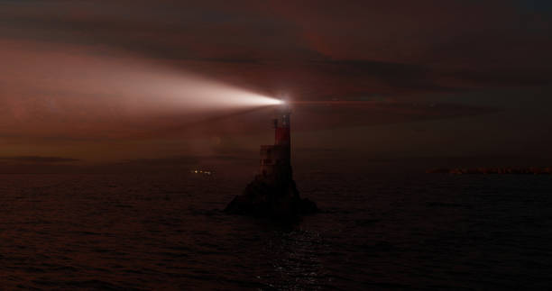 Seascape with a lighthouse in open waters at night for a stylish screen saver. Shining light house in open waters at night