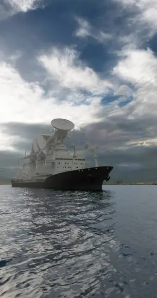 Photo of Scientific or military barge with large radio antennas pointing in the sky in a daylight against the clouded sky