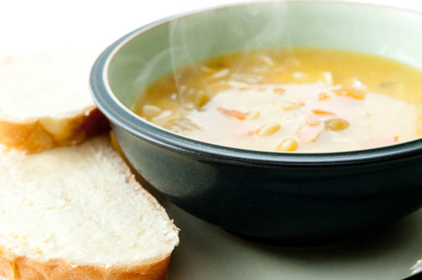 Hot chicken noodle soup and bread slices with cream cheese