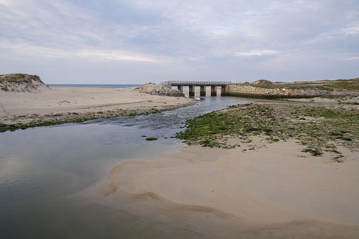 The mouth of the river and an old bridge on Baldaio beach in Carballo, Galicia, Spain