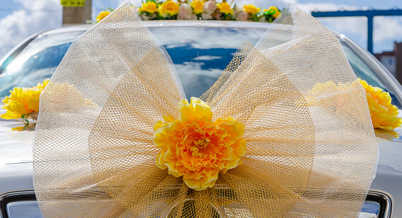 The front wedding car is decorated with large bright orange bows in the form of a flower. Wedding ceremony.