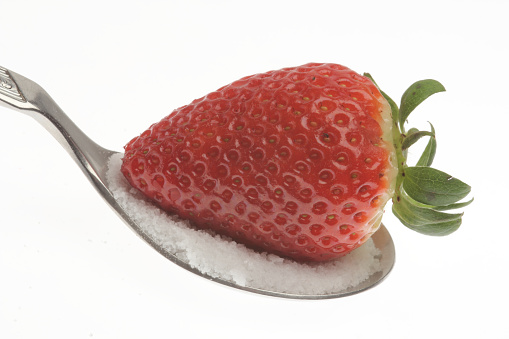 A strawberry with sugar on a spoon isolated on white background