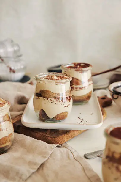 A vertical shot of delicious tiramisu in little glasses with powder on a white table