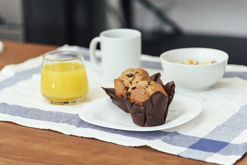 Breakfast consisting of coffee, orange juice, muffins and colored cereals. Domestic life concept.