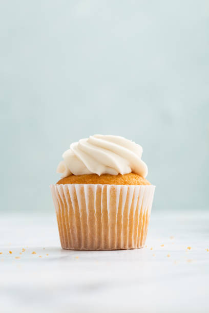 istock Vertical shot of appetizing cupcakes with cream on pastel blue background 1464967337