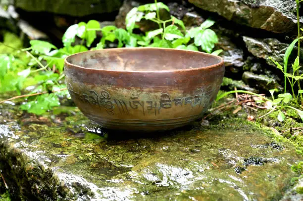 Photo of A singing bowl on a wet stone. English translation of mantras. transform your impure body