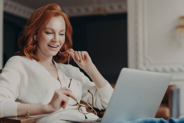 istock Satisfied happy foxy successful woman has video conference, uses modern laptop computer and earphones, browses data and works on remote project, poses in modern apartment, watches online webinar 1464970857