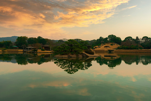 A scenic view of a lake surrounded by a landscape during sunset