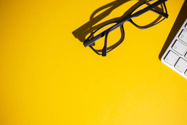 istock Top view of glasses and keyboard on a yellow work table 1464972819
