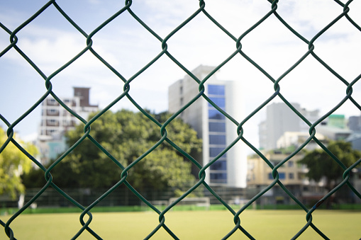 Green Chain Link Fencing background with blurred buildings back