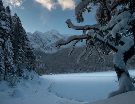 The frozen Eibsee river surrounded by trees covered with snow in Bavaria, Germany