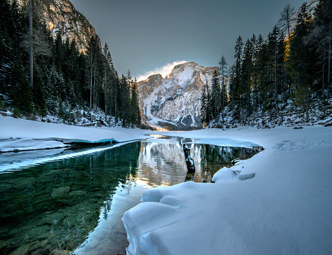 The frozen Pragser Wildsee lake surrounded by trees covered with snow in South Tyrol, Italy