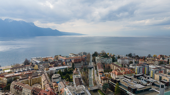 An aerial view of dense buildings near the water with mountains under the clouds in Vevey, Switzerland