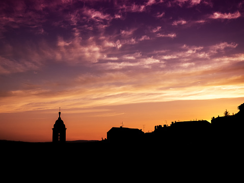 A church steeple is silhouetted by afterglow from the setting sun.