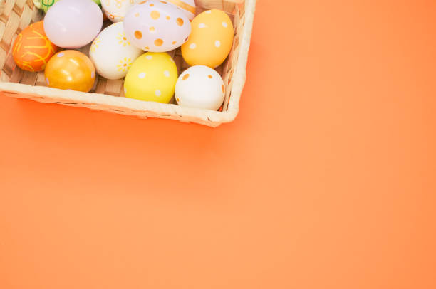 istock Woven basket with decorated eggs isolated on orange background 1464981009