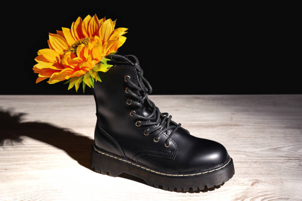 istock Yellow flower in a black boot on a wooden surface 1464982122