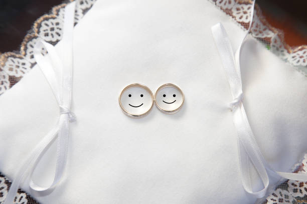 A top view of wedding rings on a white pad with drawn faces