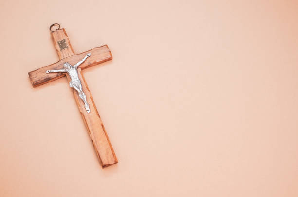 istock Wooden cross with Christ isolated on peach-colored background 1464982495