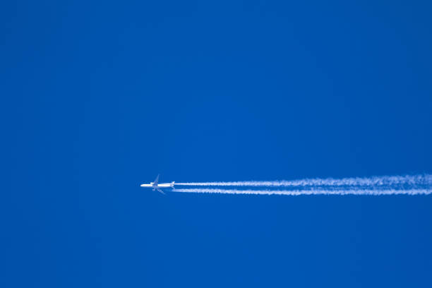 istock Passenger plane leaving a long white trail on clear blue sky 1464982964