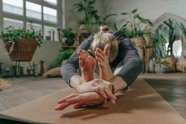 istock Man sitting in Paschimottanasana on cork mat in yoga studio 1464984204