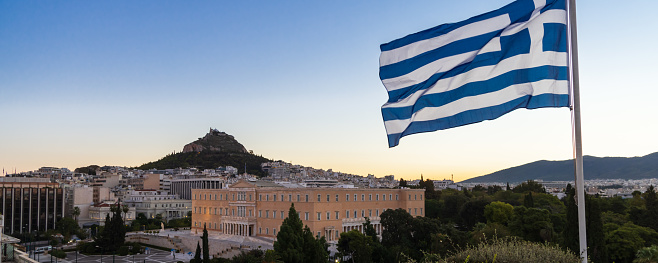 Cityscape of Athens with the Greek parliament and flag during sunset in Greece