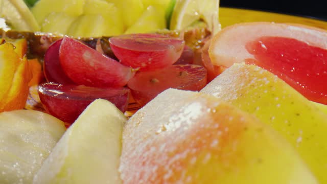 Bowl of fruits: apples with sugar, kiwi, lemons, oranges, plums, grapefruit -close up
