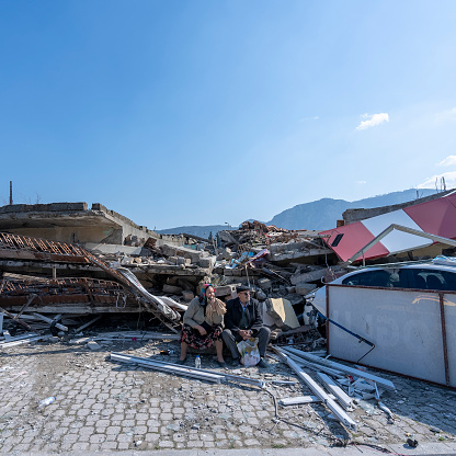 Elderly couple waiting in front of their destroyed house in Hatay