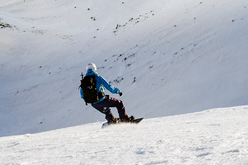 Freerider snowboarder going down the slope, back view. Adventures outdoor white winter concept